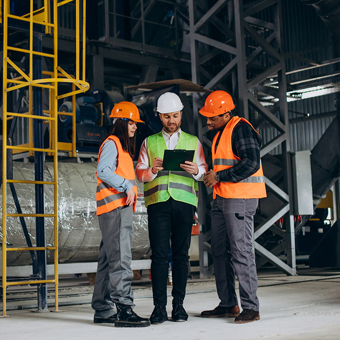 Three works in safety hats discussing business goals